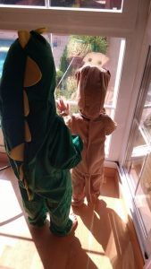 mis hijos de 2 y 4 años disfrazados de perro y dinosaurio miran por la ventana