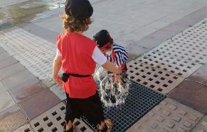 mis hijos de 2 y 54 años disfrazados de piratas jugando en una fuente de la calle
