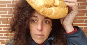 Primer plano de mi rostro sosteniendo una horas a de pan sobre mi cabeza