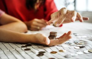 primer plano de manos contando monedas sobre una mesa