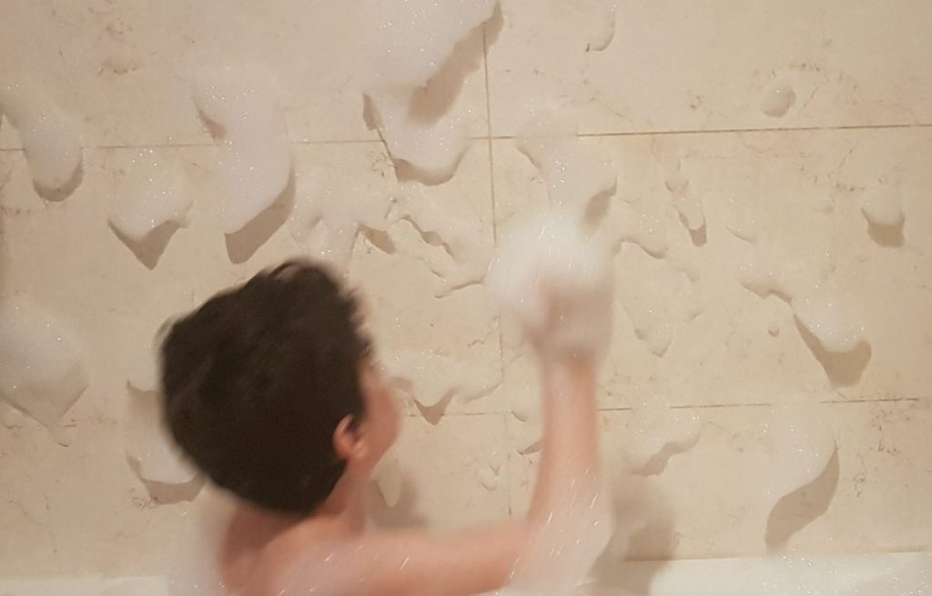 Mi hijo de 6 años formando nubes en la pared con la espuma de la bañera
