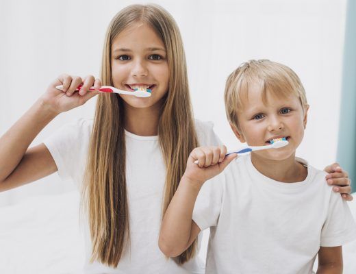 un niño y una niña cepillandose los dientes