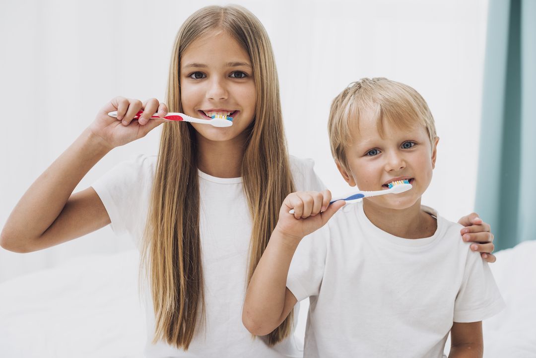 un niño y una niña cepillandose los dientes