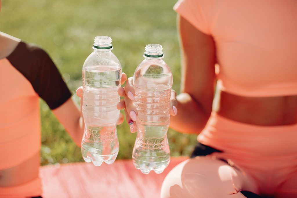 madre e hijo sentados en el parque con una botella de agua en la mano cada uno