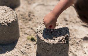 mano infantil haciendo un castillo de arena