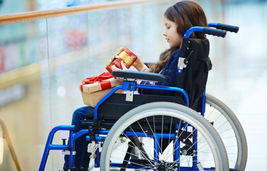 niña en silla de ruedas sosteniendo dos regalos