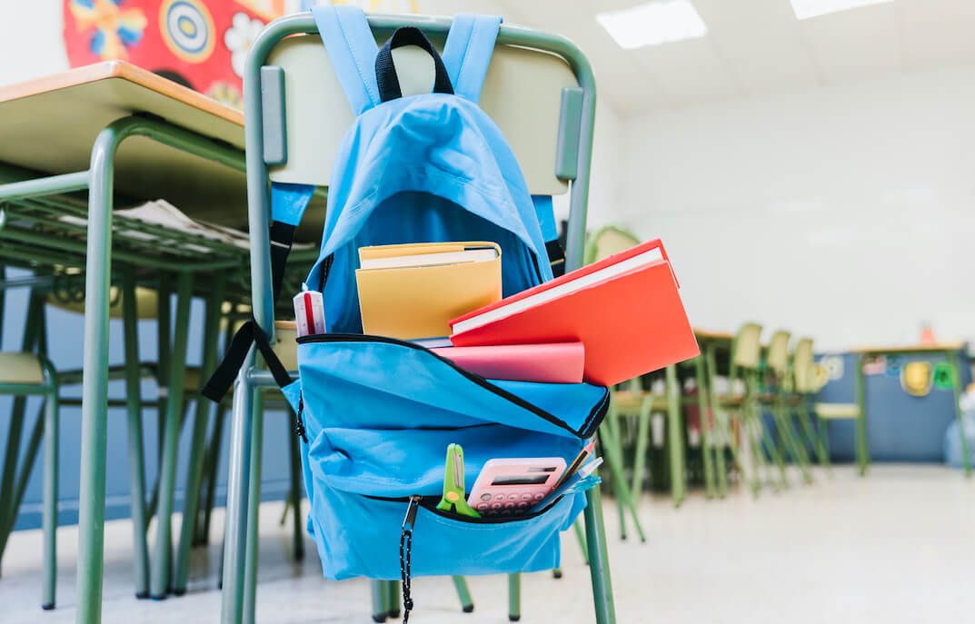mochila colgada en el respaldo de una silla en una clase de escuela