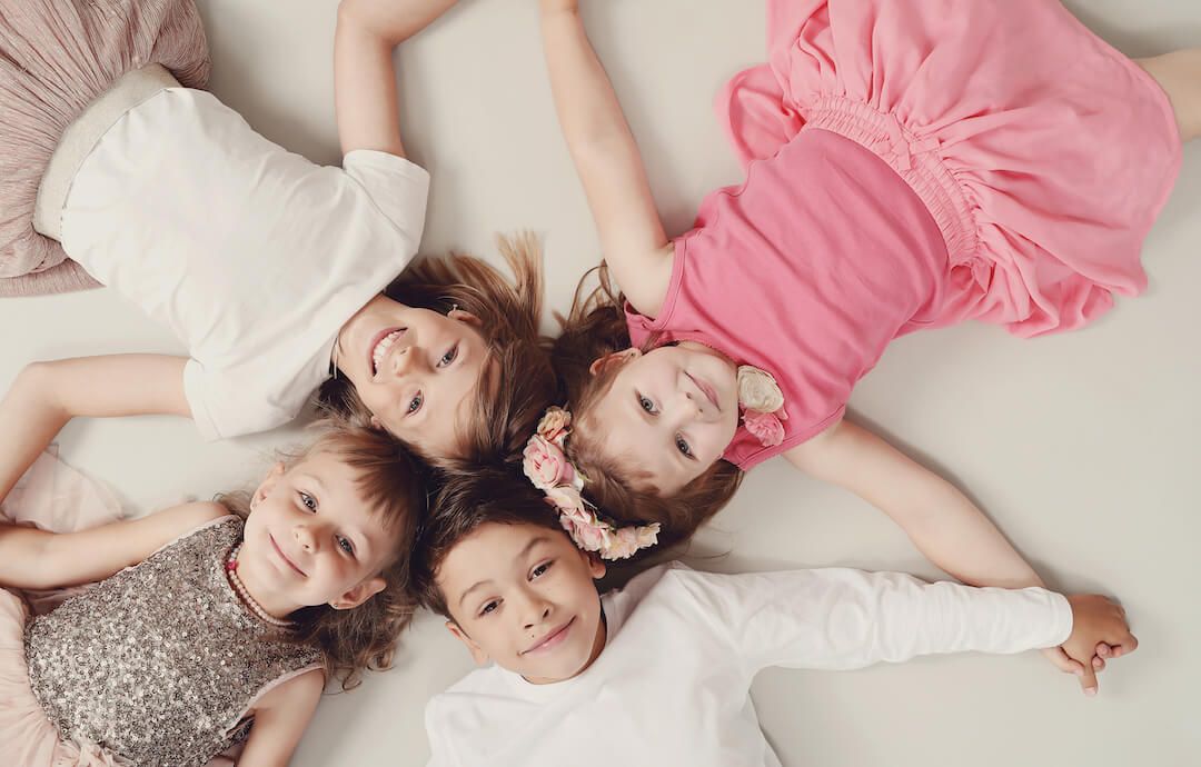 4 niños y niñas recostados en el suelo sonriendo