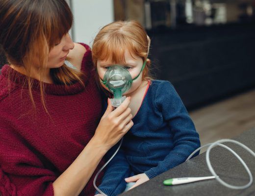 madre colocando un respirador en la cara de una niña sentada en su regazo