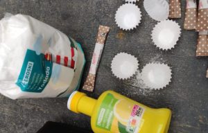 botella de zumo de limón exprimido, paquete de sal, bolsitas de papel individuales de azúcar moreno y unos mini moldes de papel para hornear madalenas con sal.