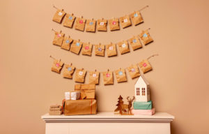 foto de un calendario de adviento de bolsas de papel kraft colgadas en tres lineas de cuerdas, sobre un recibidor con decoraciones navideñas