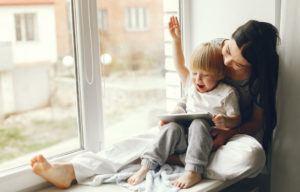 madre con niño pequeño leyendo sentados en una ventana