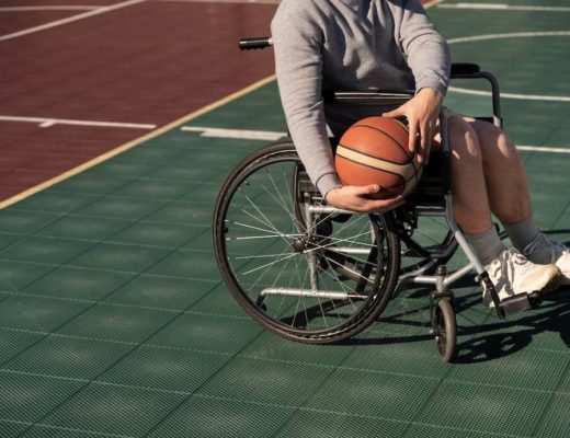 chico en silla de ruedas en pista de bañoncesto con una pelota en las manos