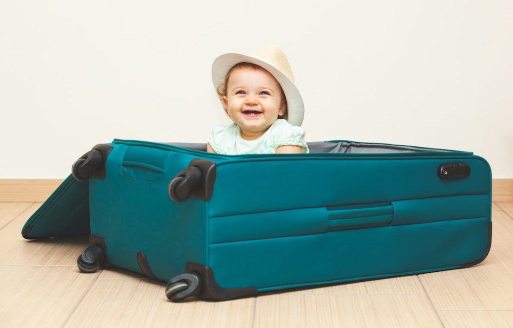 niña pequeña dentro de una maleta sonriendo