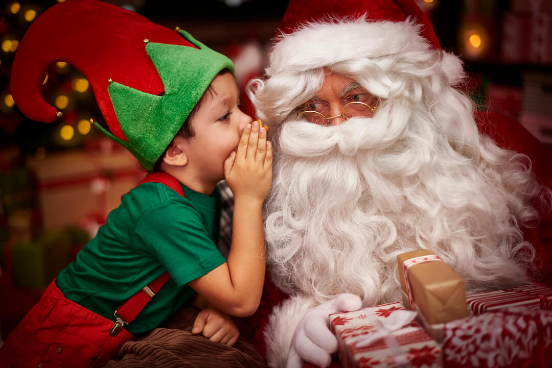 niño cuenta un secreto a papa Noel
