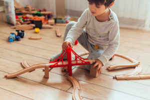 niño jugando en el suelo con unos puentes de madera