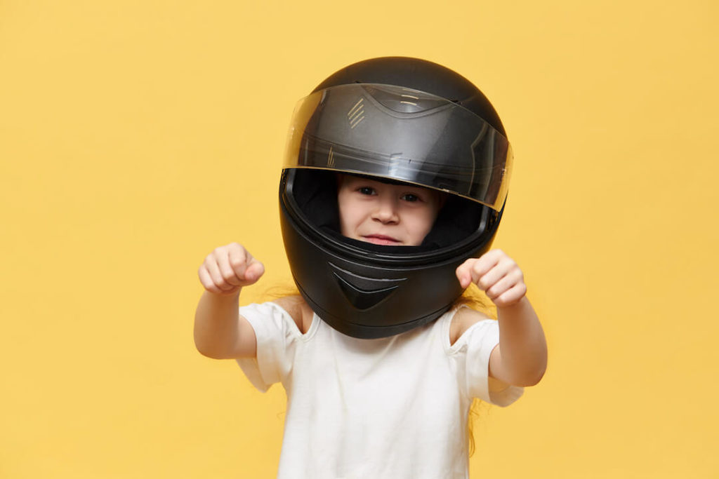 niña con casco de moto imita con los brazos la conducción