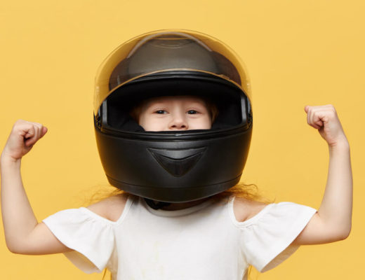 niña con casco de moto hace un gesto de fuerza con los brazos