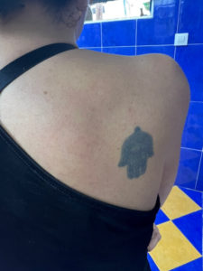 foto de mi espalda con un pequeño tatuaje verde de una mano de fátima