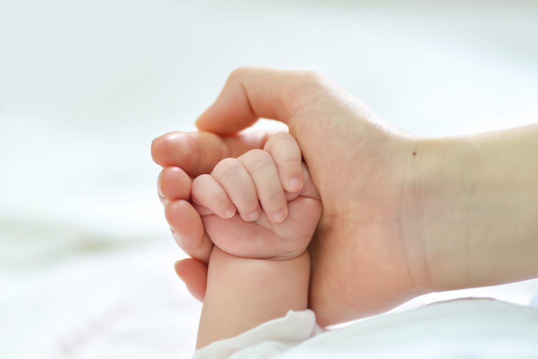 foto de una mano de mujer sosteniendo la mano de un bebé