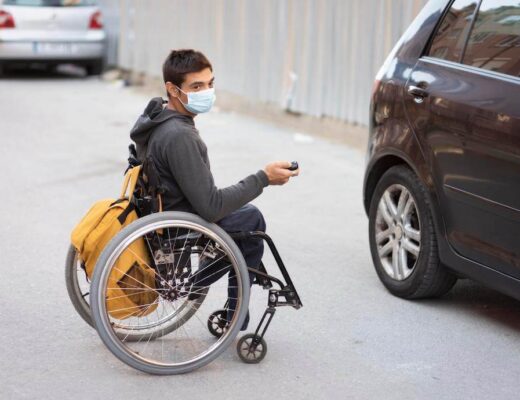 hombre joven sentado en una silla de ruedas abriendo un coche con la llave a distancia