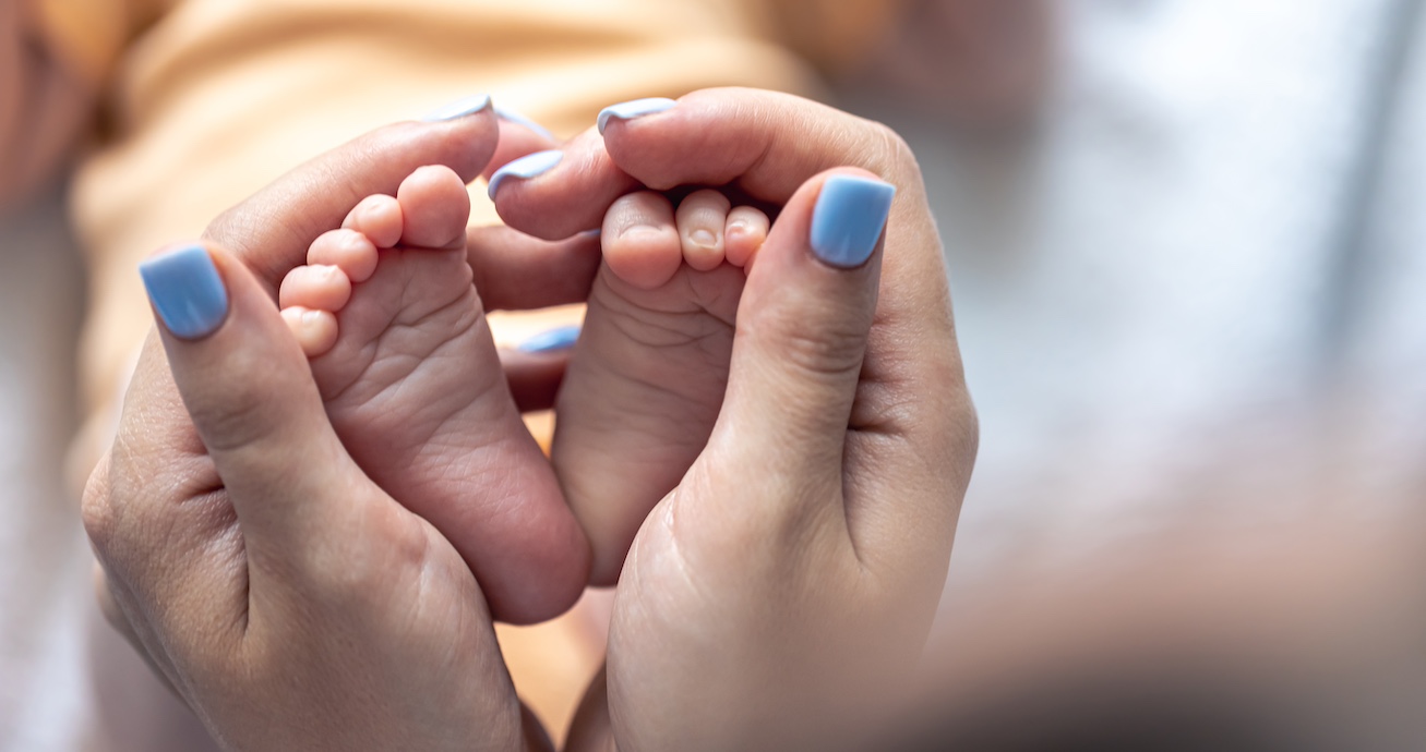 manos de mujer cogiendo los pies de un bebé